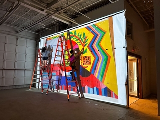 Artists working on a full size canvas of the Take the Risk to Cool Down Mural